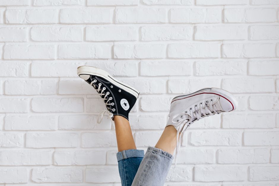 Two pairs of Converse sneakers against a white brick wall. Stylish and casual fashion statement.
