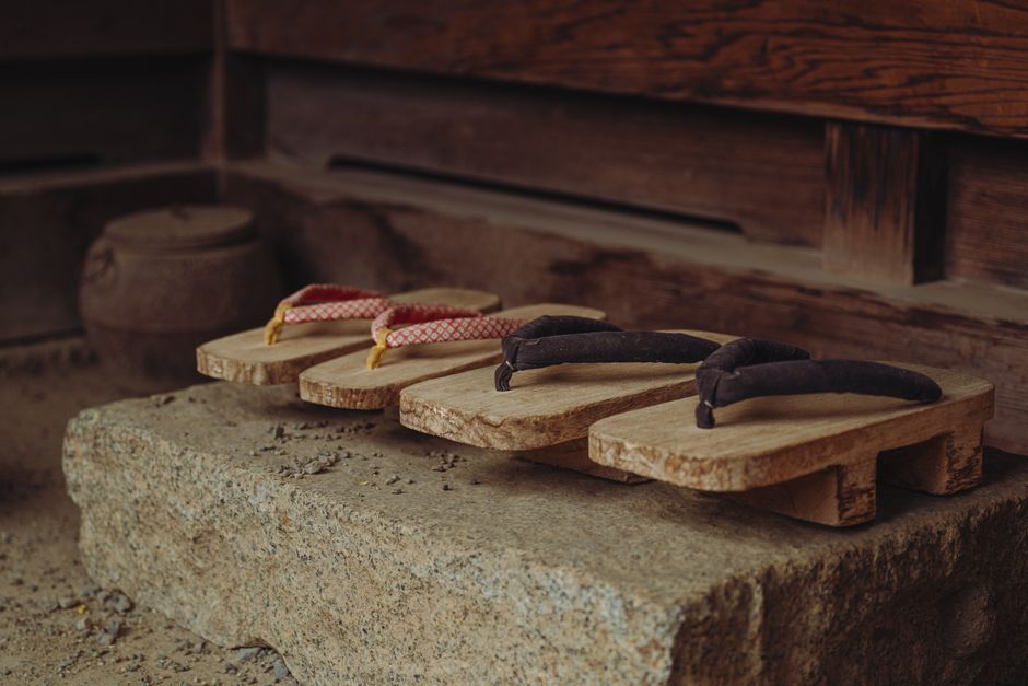 Highlighted shot of Japanese geta sandals resting on a rustic stone surface, capturing cultural tradition.