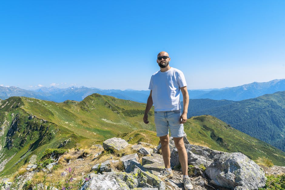 A man stands on a rocky peak enjoying a stunning mountain view in Гагра, perfect for adventure and travel inspiration.