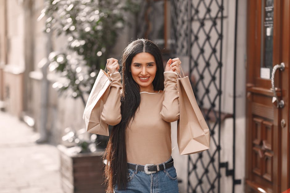 Happy young woman with long dark hair looking excitedly at camera holding papers bags after successful shopping