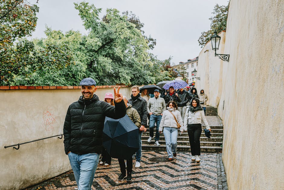 Group of tourists with umbrellas walking down a charming European street during a rainy day.