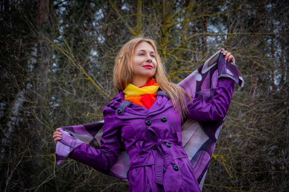 Stylish woman in vibrant purple coat and scarf enjoying a crisp autumn day outdoors.