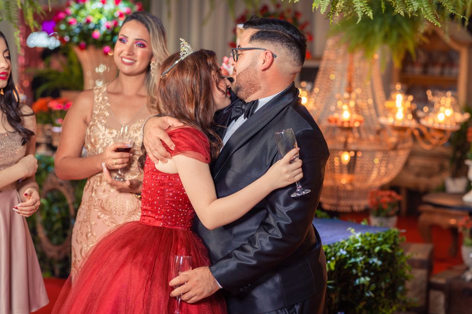 Friends in formal attire celebrate with hugs and champagne at a luxurious indoor party.