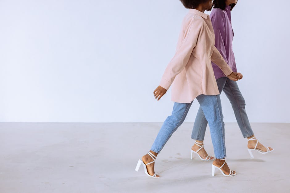 Two women in trendy attire walking against a white background showing modern fashion sense.