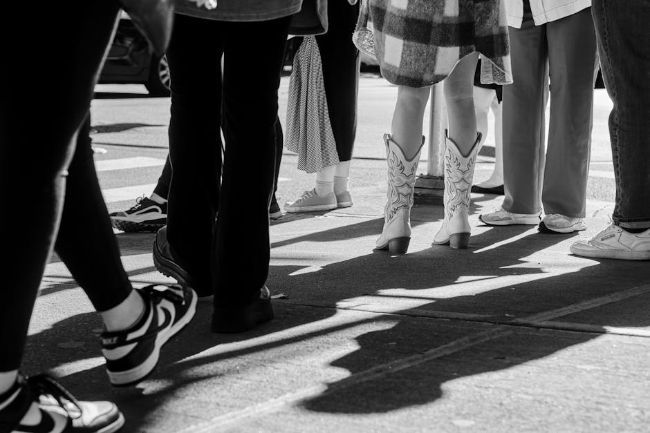 Black and white photo capturing people and shadows on a city street.