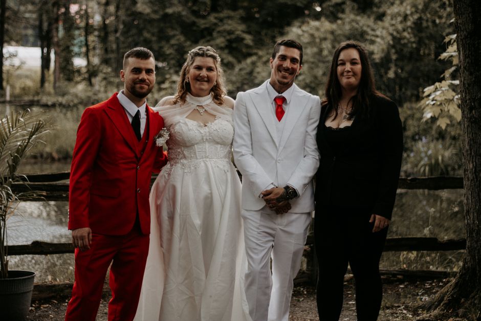 A group portrait from an outdoor wedding featuring elegantly dressed celebrants in nature.