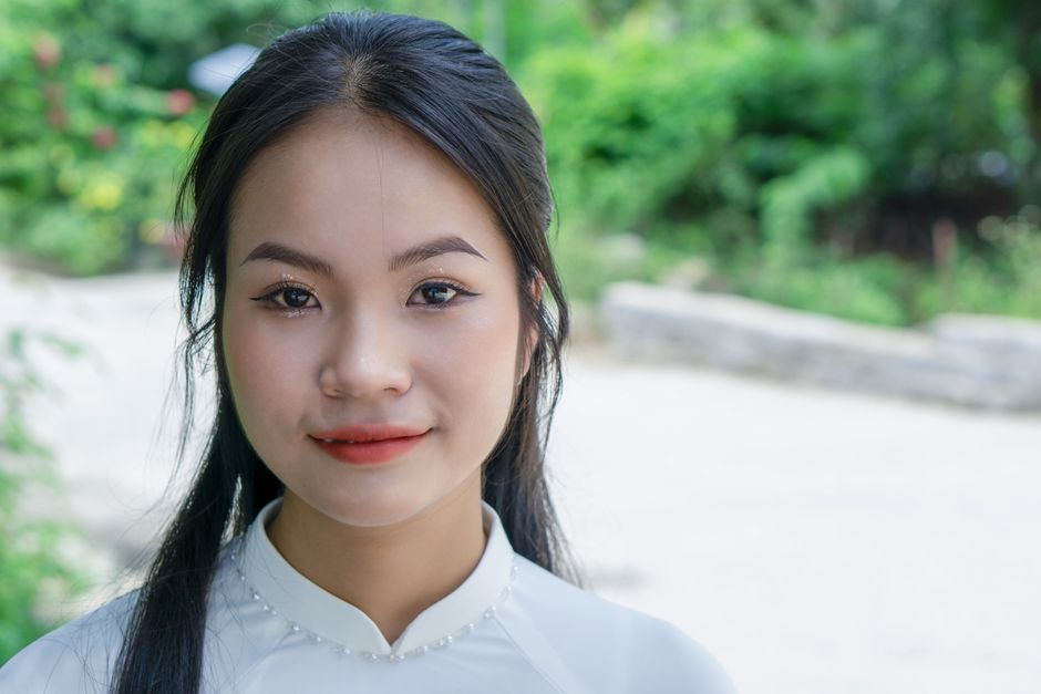 Elegant portrait of a young woman with natural makeup and long hair, shot outdoors against