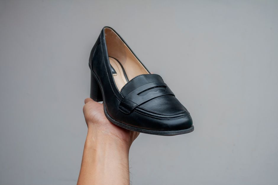 A detailed view of a black leather loafer being held, showcasing its craftsmanship.