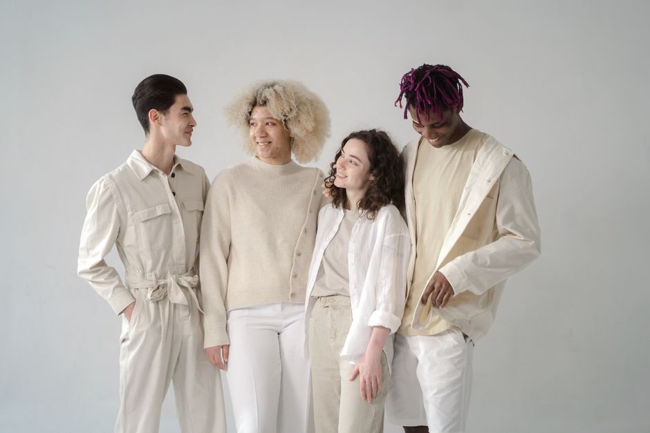 A diverse group of friends dressed stylishly, smiling in a studio setting.