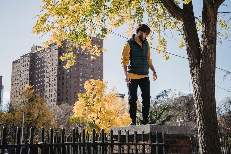 Full body of bearded male in casual wear standing on brick construction and looking down