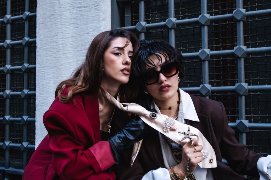 Chic urban portrait of two stylish women in fashionable outfits with accessories.