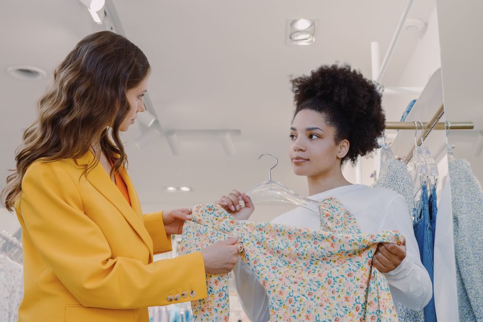 Two women browsing floral dresses in a chic boutique store.