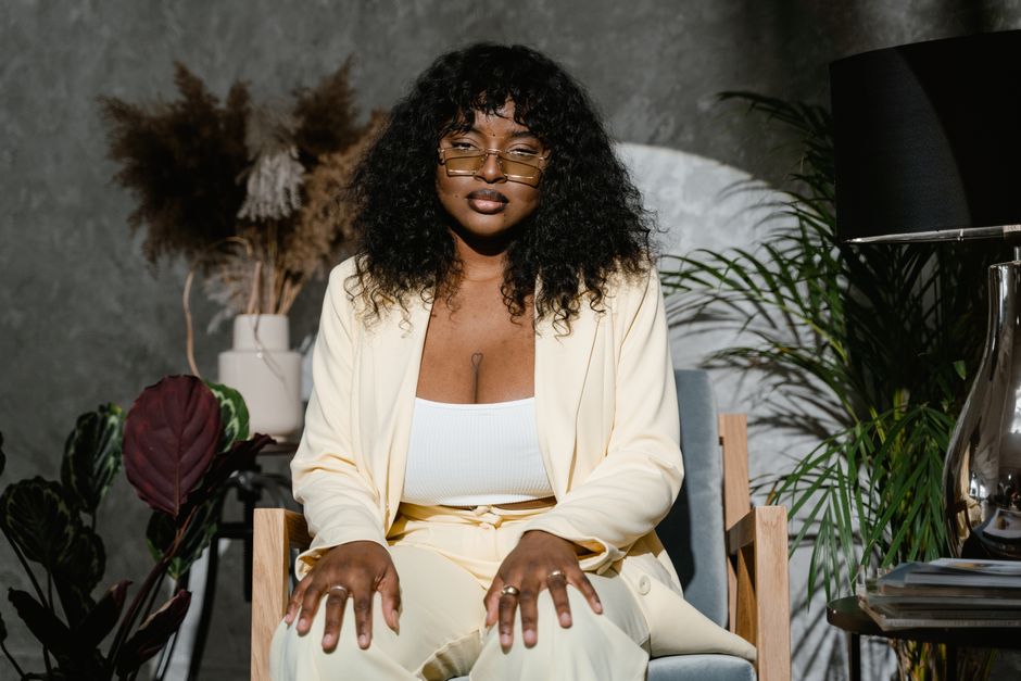 Portrait of a confident plus size woman seated indoors, conveying self-esteem and individuality.