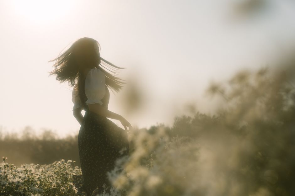 Ethereal silhouette of a woman dancing in a flowery field at sunset, Lạng Sơn, Vietnam.