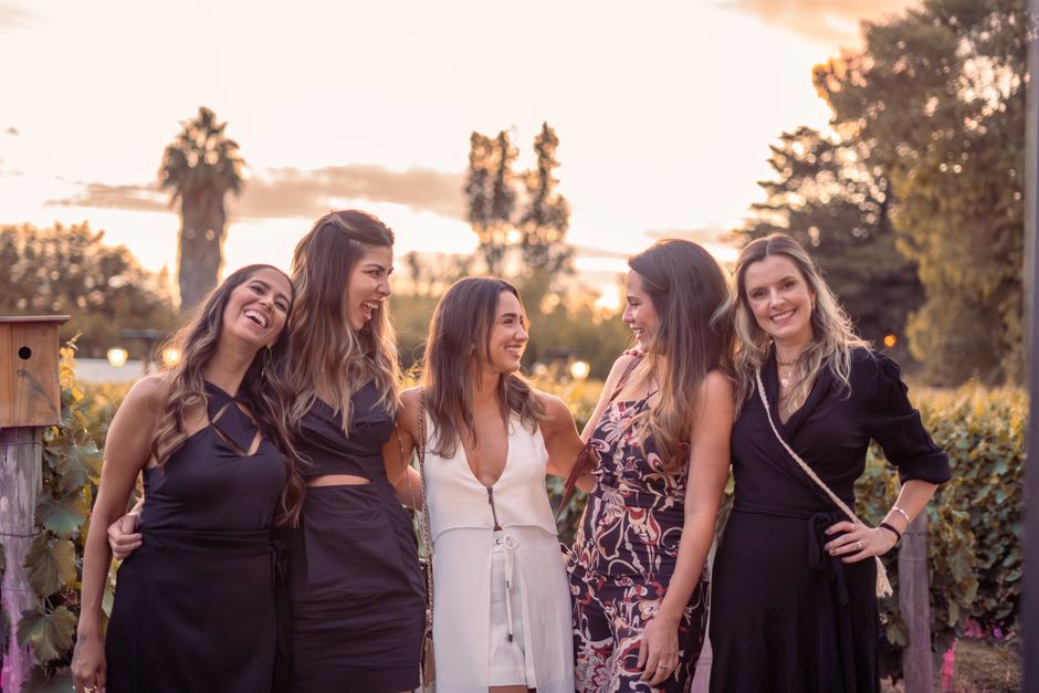 Five women enjoying a sunset gathering with elegance and smiles outdoors.