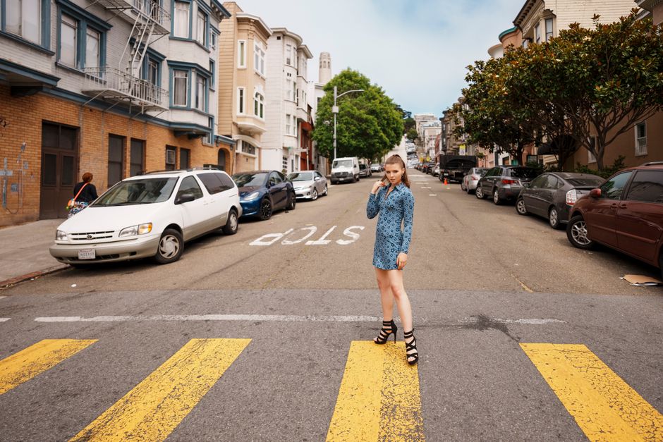 Young woman in blue dress crossing a street in San Francisco's urban neighborhood.