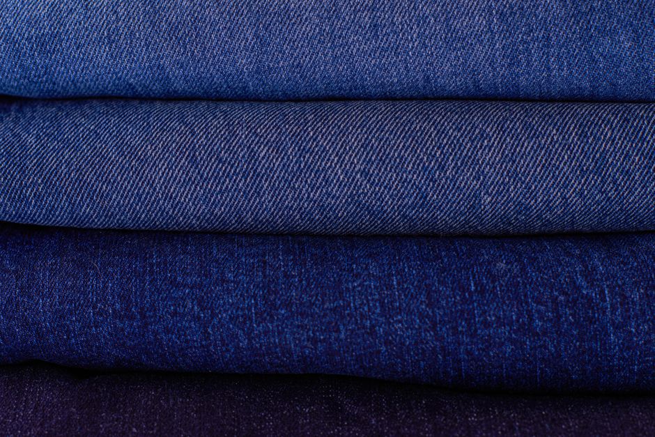 Close-up of neatly stacked folded denim fabrics in varying blue tones showcasing texture and pattern.