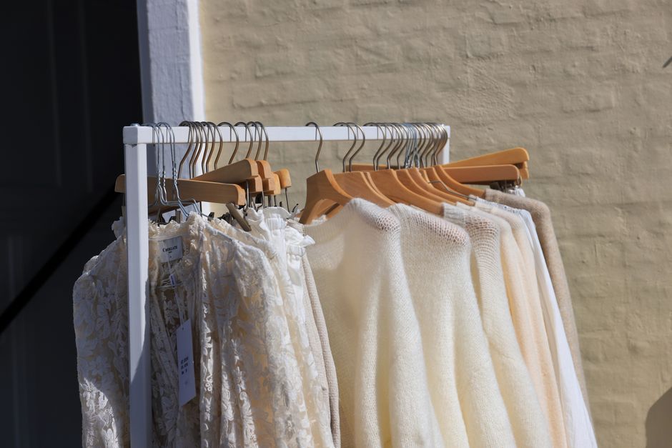 A collection of elegant sweaters and dresses on a rack in Løkken, Denmark's outdoor clothing store.