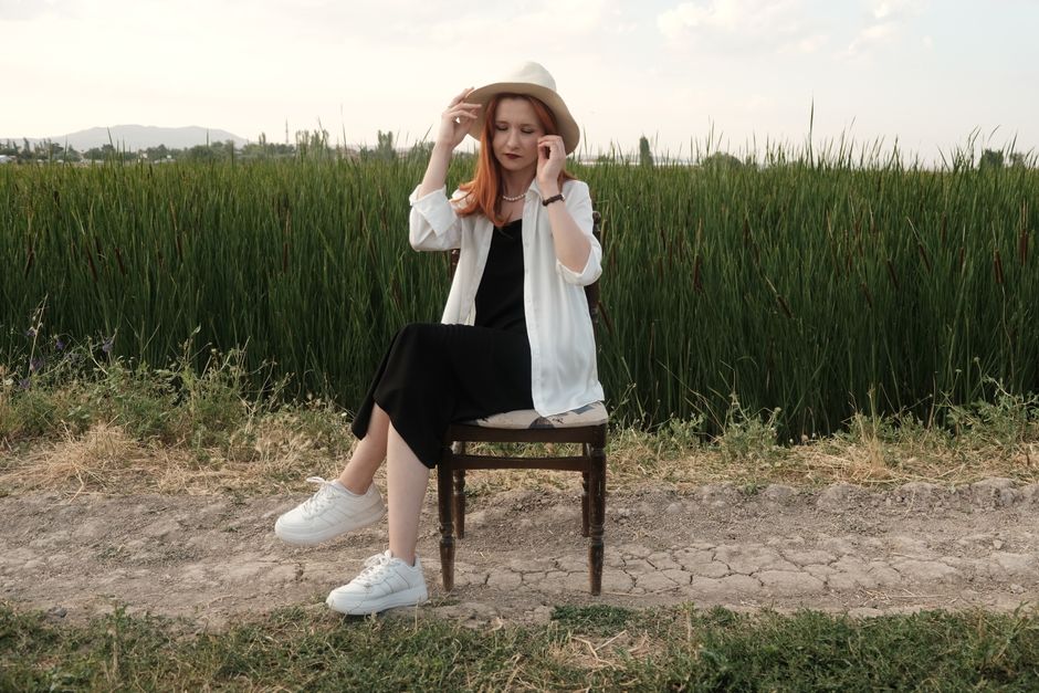 Stylish woman in countryside setting, enjoying the serene outdoor atmosphere.