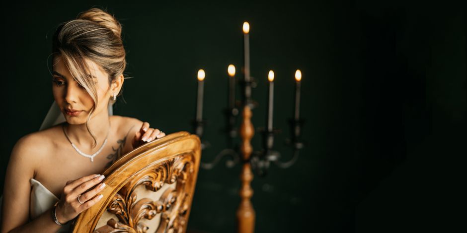 Stunning bride with vintage candelabra in dimly lit setting, exuding elegance and charm.