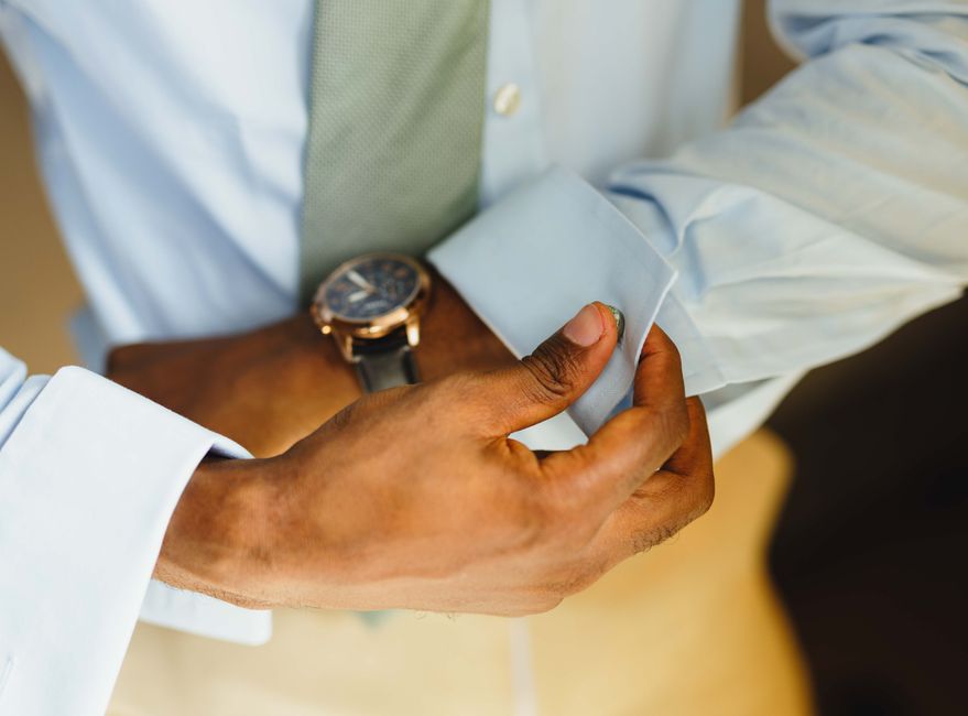 Close-up of a man adjusting his shirt cuff wearing a watch, highlighting business attire.